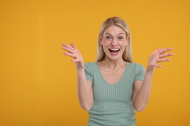 Portrait of happy surprised woman on yellow background, space for text