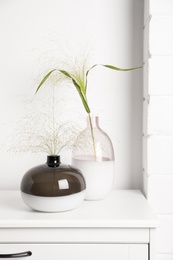 Photo of Decorative vases with plants on commode indoors