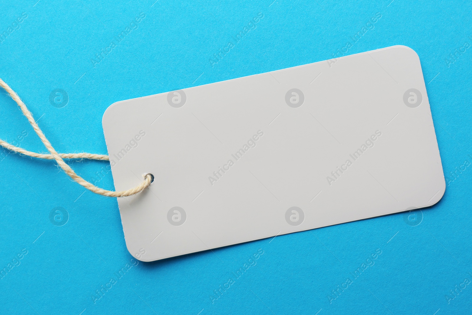 Photo of Tag with space for text on light blue background, top view