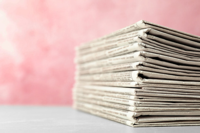 Photo of Stack of newspapers on pink background, closeup. Journalist's work