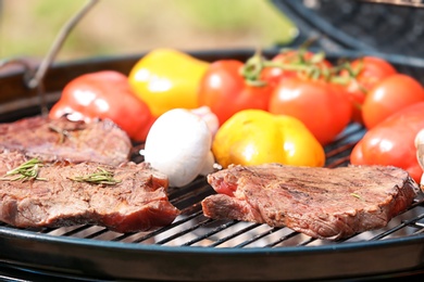 Photo of Barbecue grill with meat and vegetables outdoors, closeup