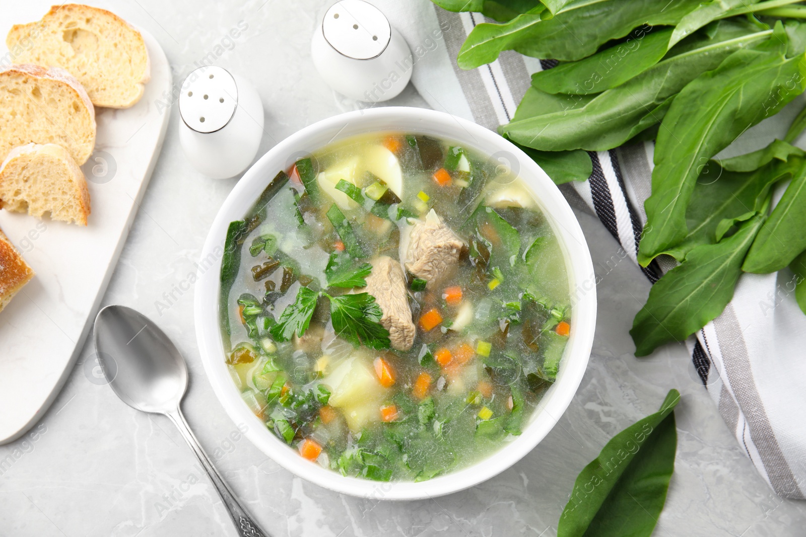 Photo of Delicious sorrel soup with meat served on marble table, flat lay