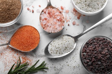 Flat lay composition with different kinds of salt on white marble table