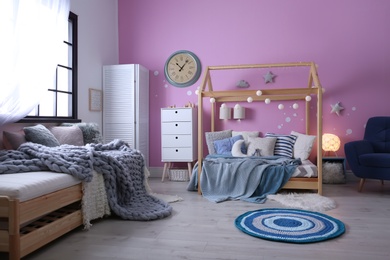 Photo of Child's room interior with comfortable bed and garland