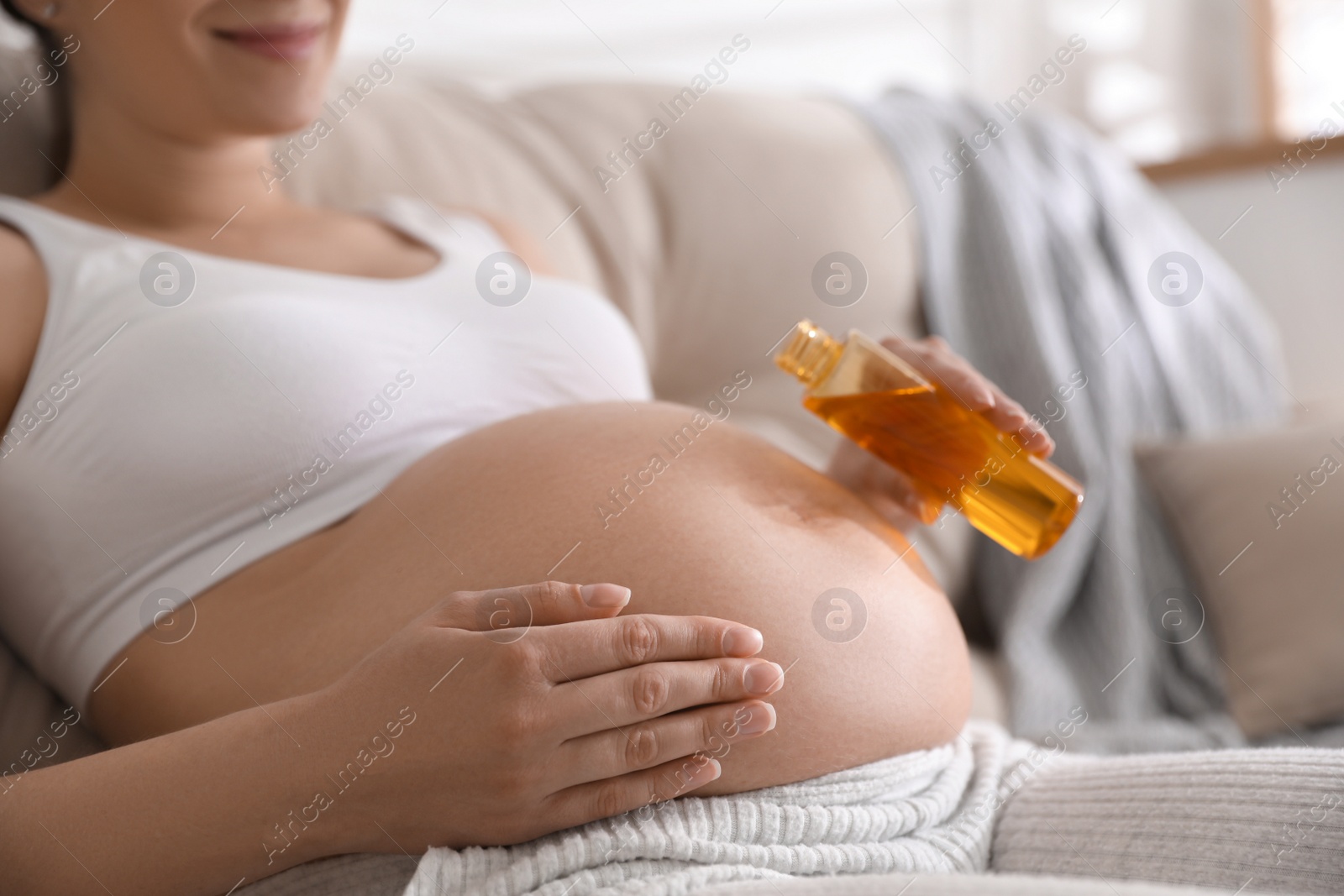 Photo of Young pregnant woman with cosmetic product indoors, closeup