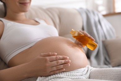 Photo of Young pregnant woman with cosmetic product indoors, closeup