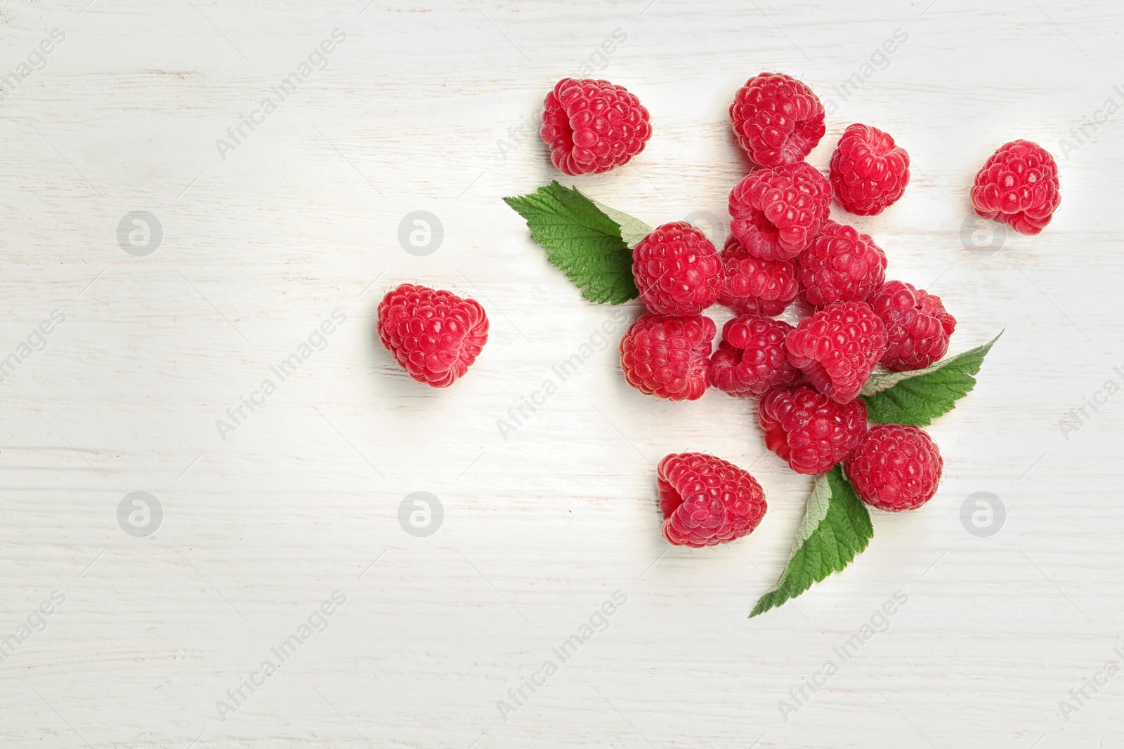 Photo of Ripe aromatic raspberries on wooden table, top view