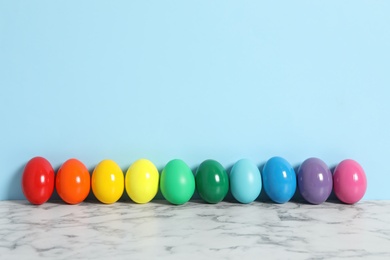 Easter eggs on white marble table against light blue background, space for text
