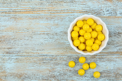 Photo of Delicious lemon chewing gums on light blue wooden background, flat lay. Space for text