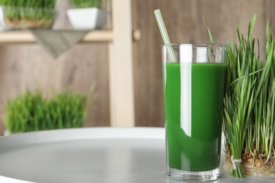 Photo of Glass of juice and sprouted wheat grass on table. Space for text