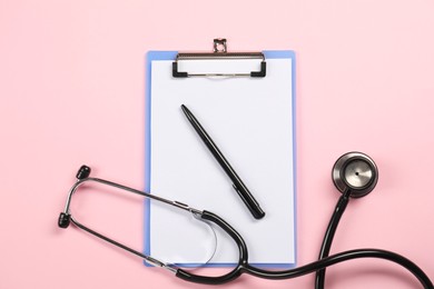 Endocrinology. Stethoscope, clipboard and pen on pink background, top view