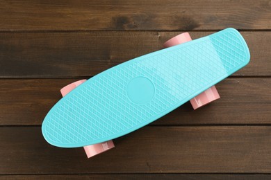 Photo of Turquoise skateboard on wooden background, top view. Sport equipment