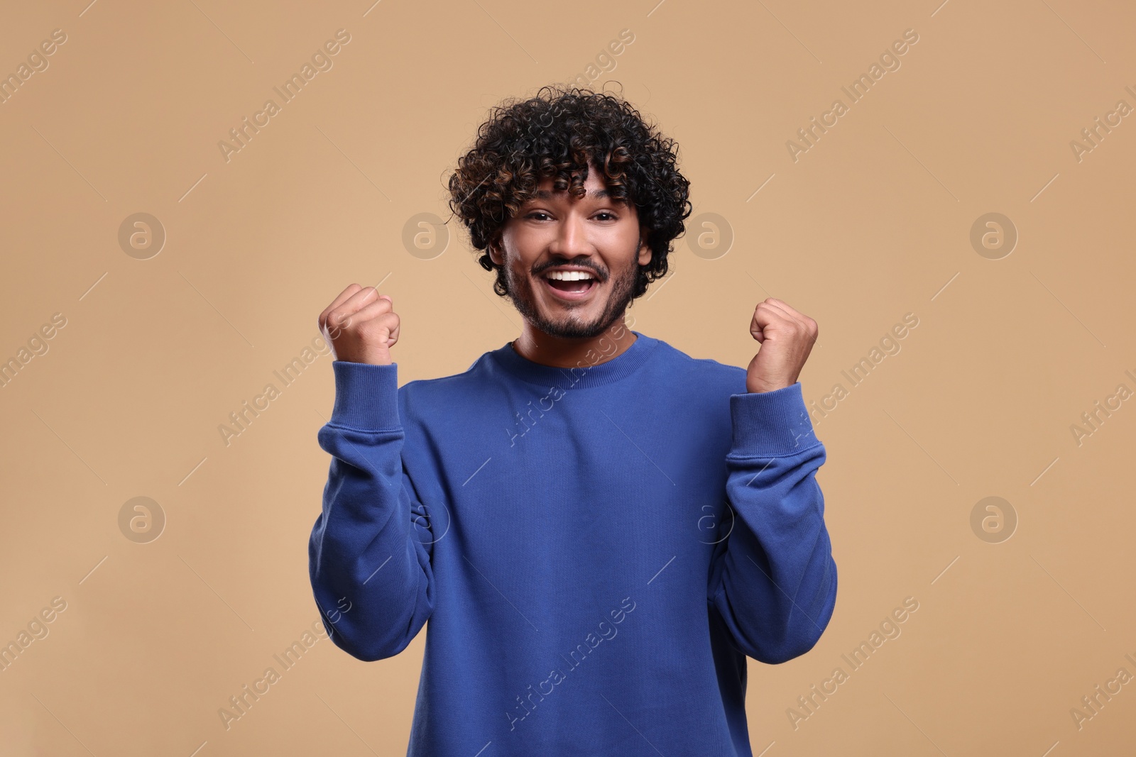 Photo of Handsome young happy man on beige background