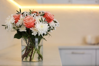 Vase with beautiful flowers on countertop in kitchen, space for text. Interior design