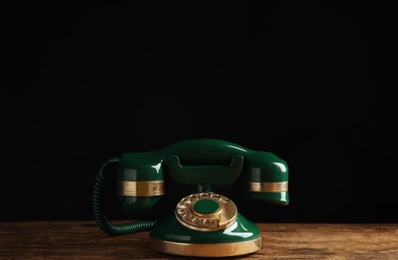 Photo of Vintage corded phone on wooden table against black background