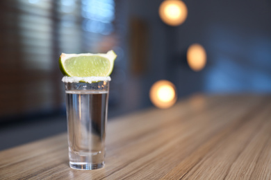 Photo of Mexican Tequila with salt and lime slice on bar counter. Space for text