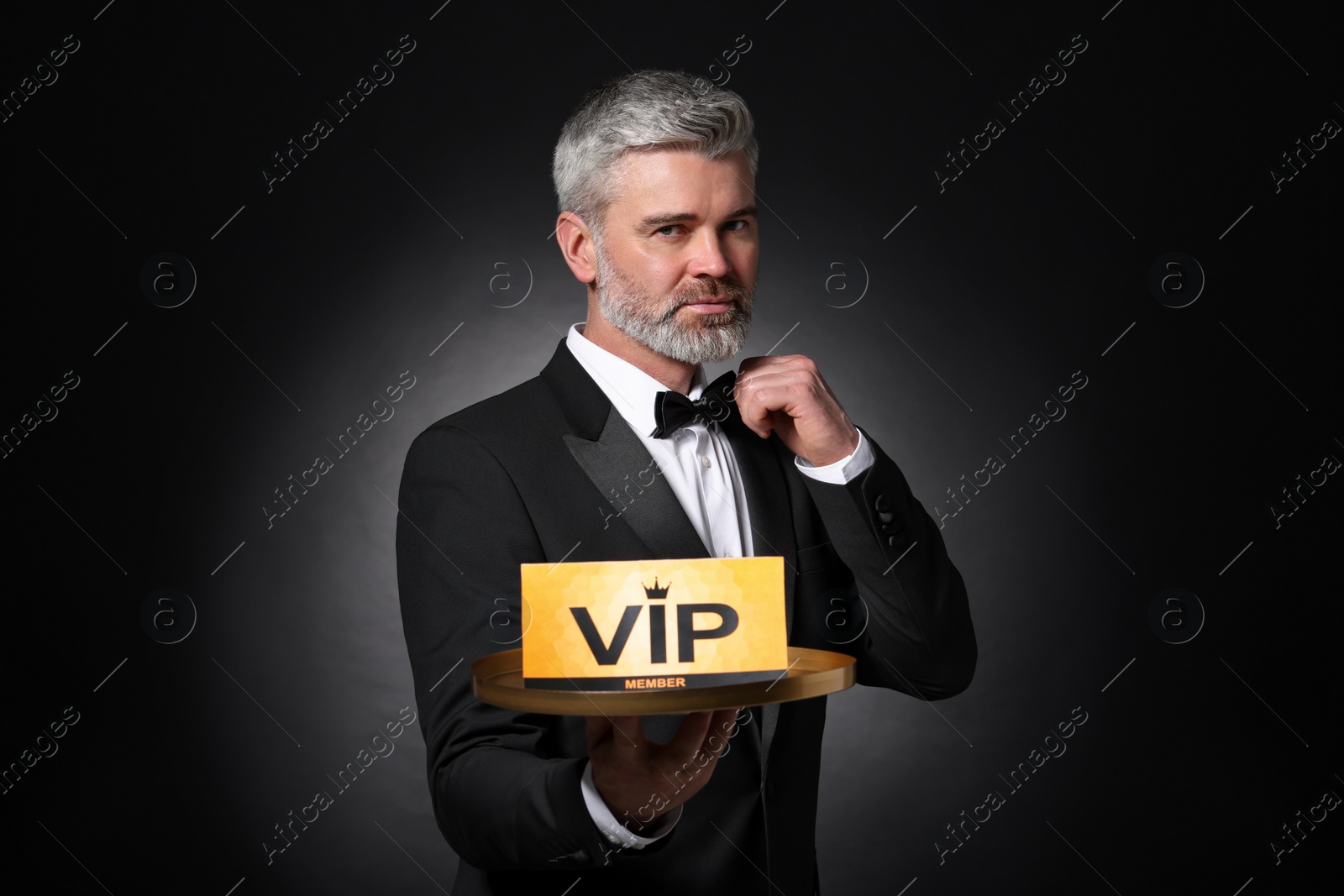 Photo of Handsome man holding tray with VIP sign on black background