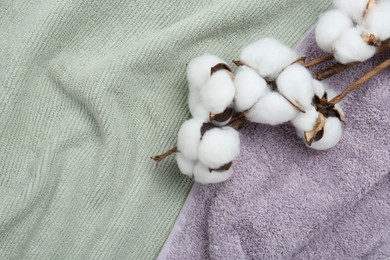 Photo of Cotton flowers on soft towels, top view. Space for text