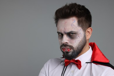 Photo of Man in scary vampire costume with fangs on light grey background, space for text. Halloween celebration