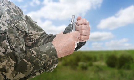 Image of Soldier pulling safety pin out of hand grenade outdoors, closeup