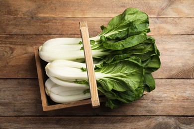 Photo of Fresh green pak choy cabbages in crate on wooden table, top view