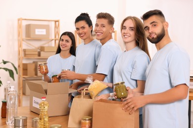 Photo of Portrait of volunteers packing food products at table in warehouse