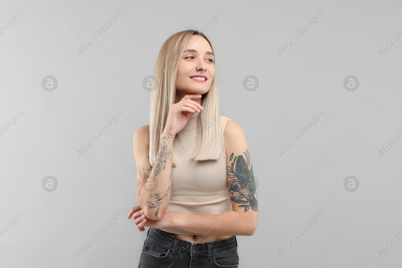 Photo of Portrait of beautiful tattooed woman on gray background