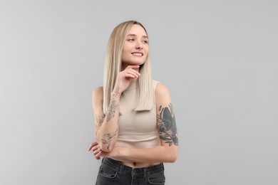 Portrait of beautiful tattooed woman on gray background