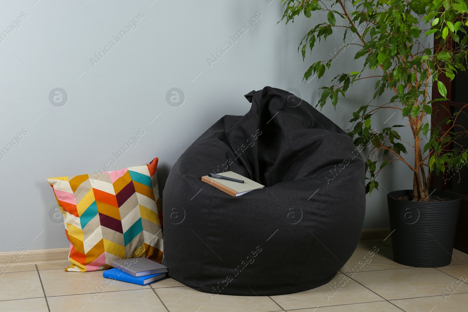 Photo of Black cozy bean bag chair near light grey wall in room
