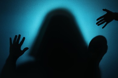 Silhouette of ghosts behind glass against blue background
