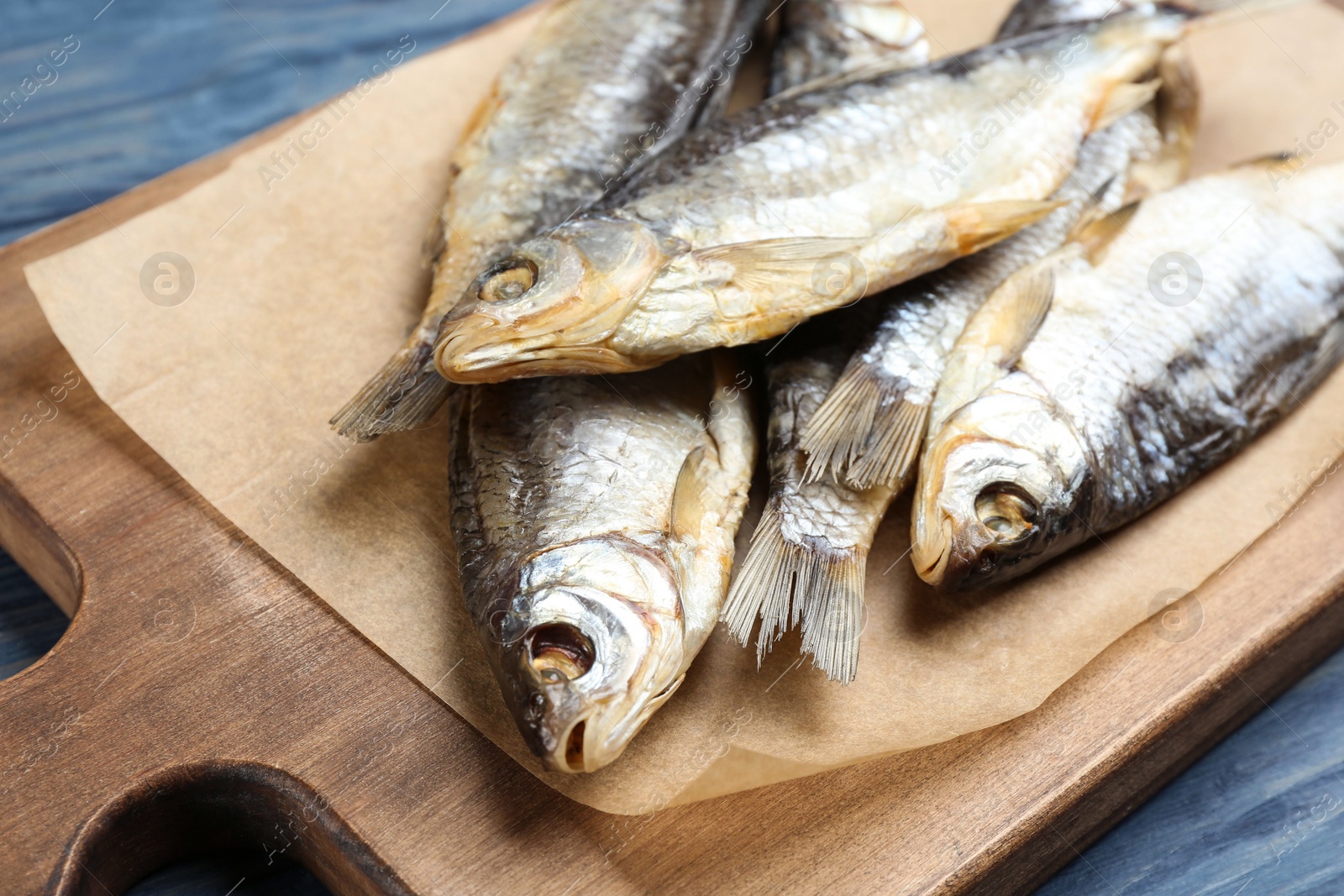 Photo of Tasty dried fish on blue wooden table, closeup