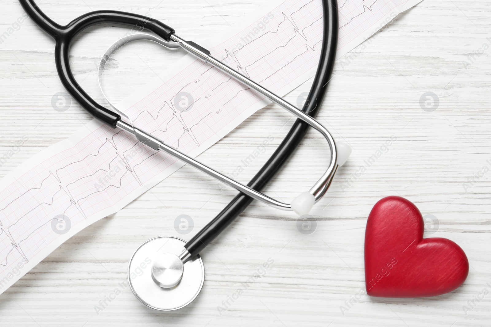 Photo of Cardiogram report, red heart and stethoscope on white wooden table, flat lay