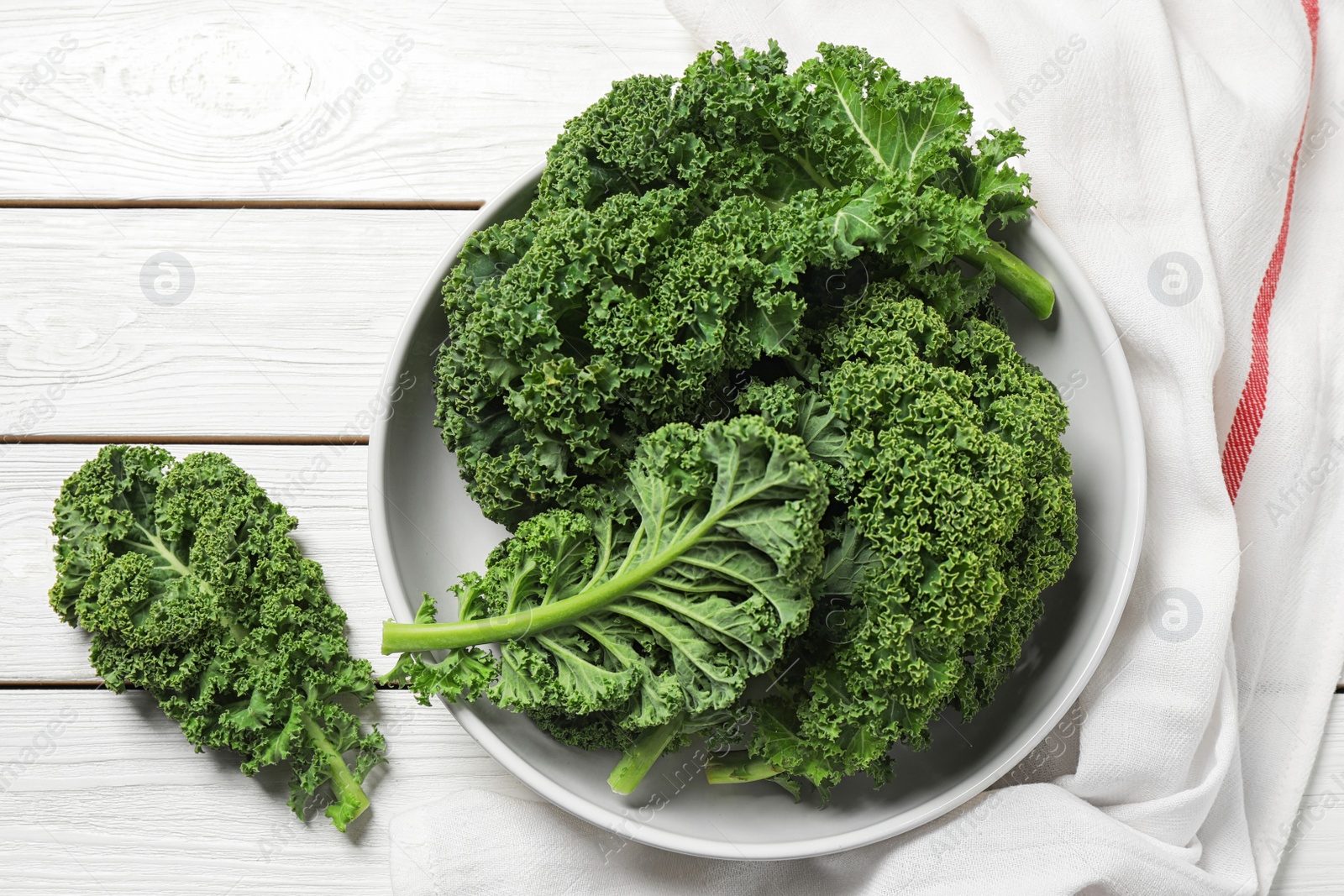 Photo of Fresh kale leaves on white wooden table, flat lay