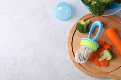 Photo of Nibbler with boiled broccoli and carrot on light grey table, flat lay. Space for text