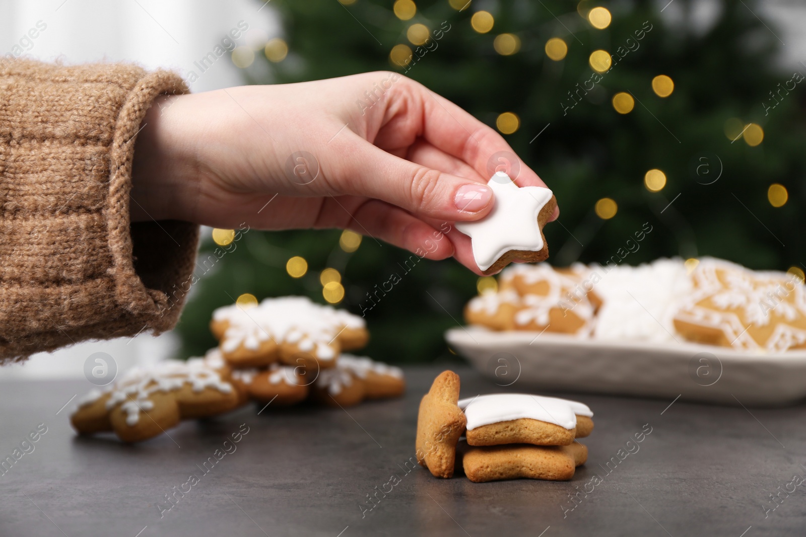 Photo of Woman with decorated Christmas cookies at table, closeup