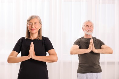 Photo of Senior couple practicing yoga indoors, selective focus