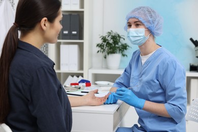 Photo of Laboratory testing. Doctor taking blood sample from patient at white table in hospital