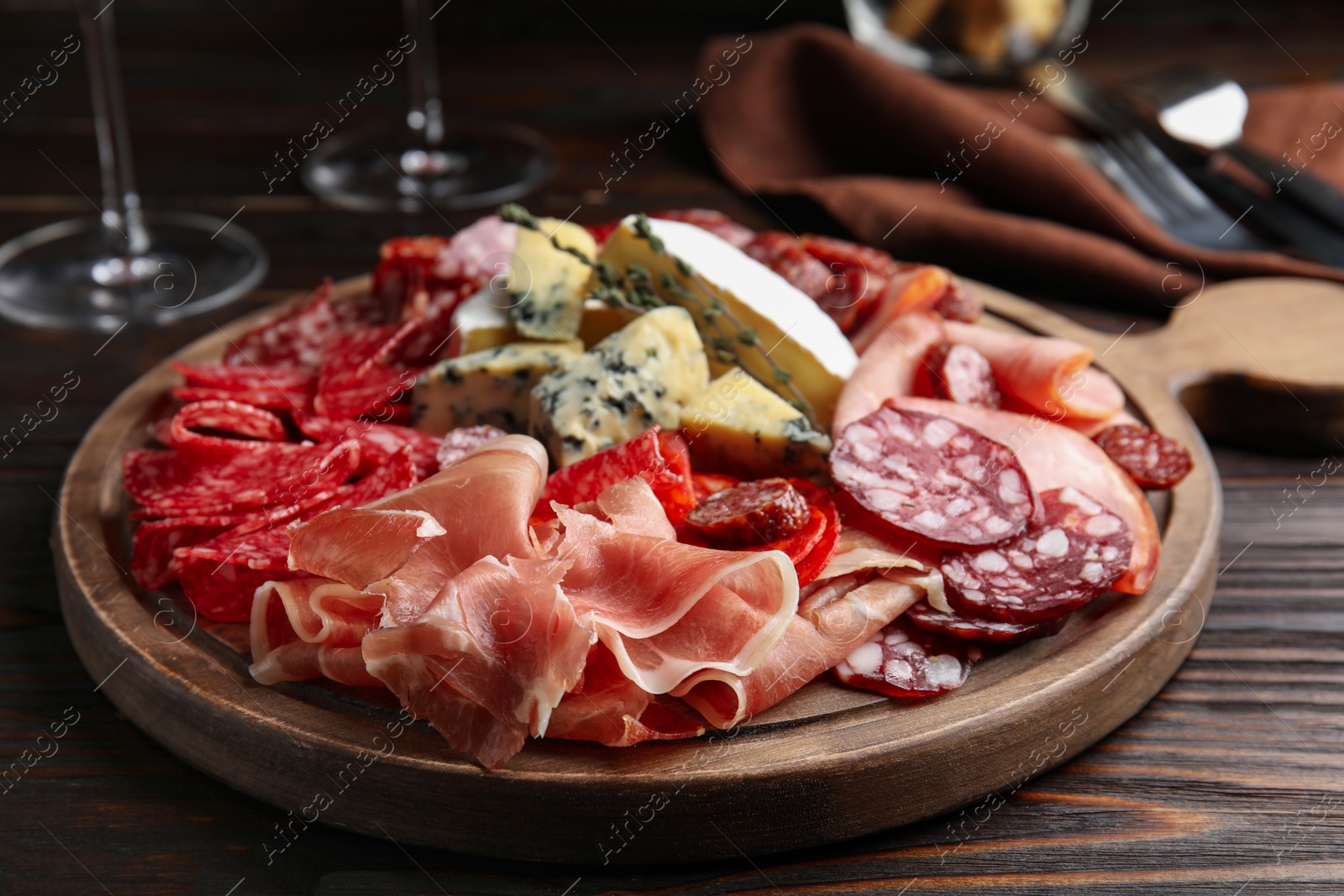 Photo of Tasty prosciutto with other delicacies served on wooden table