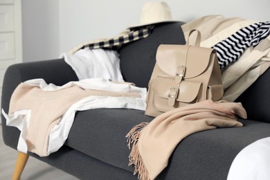 Photo of Messy pile of clothes on sofa in living room