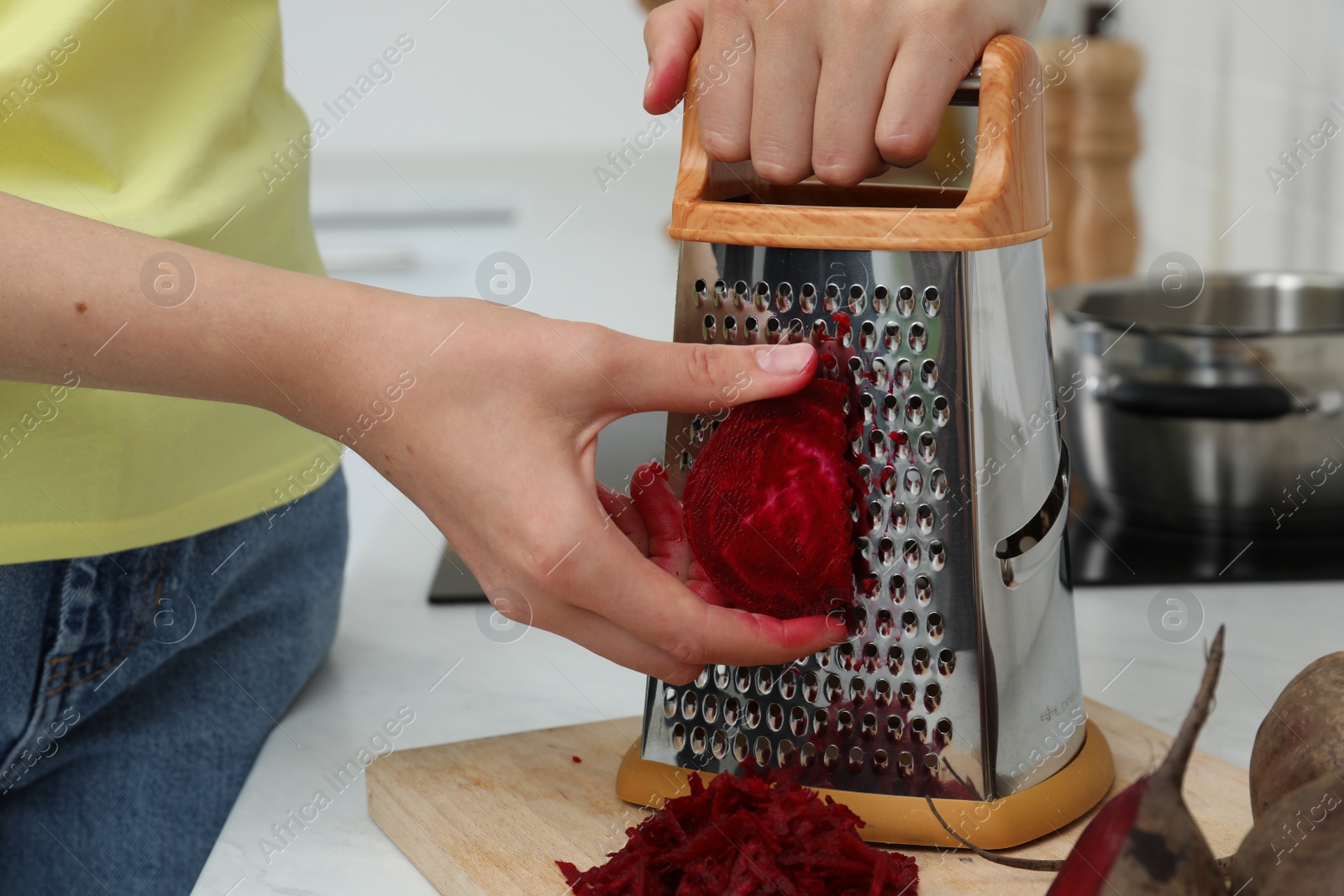 Photo of Woman grating fresh beetroot at kitchen counter, closeup