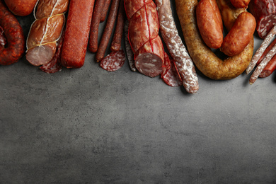 Photo of Different types of sausages on grey background, flat lay. Space for text