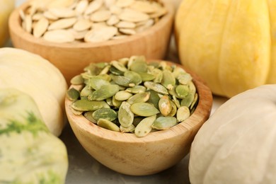 Photo of Bowls with seeds and fresh pumpkins on table, closeup