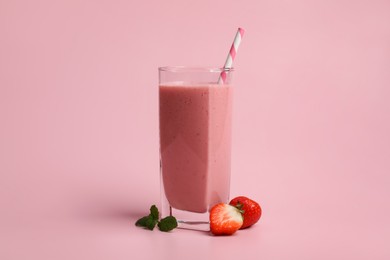 Photo of Glass with delicious berry smoothie and fresh strawberries on pink background