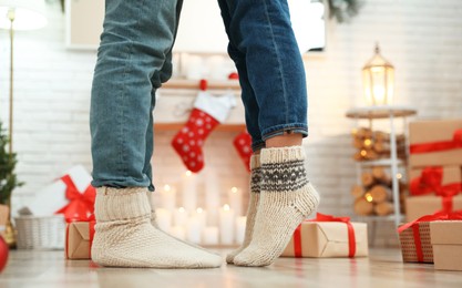 Couple in warm socks in room decorated for Christmas, closeup