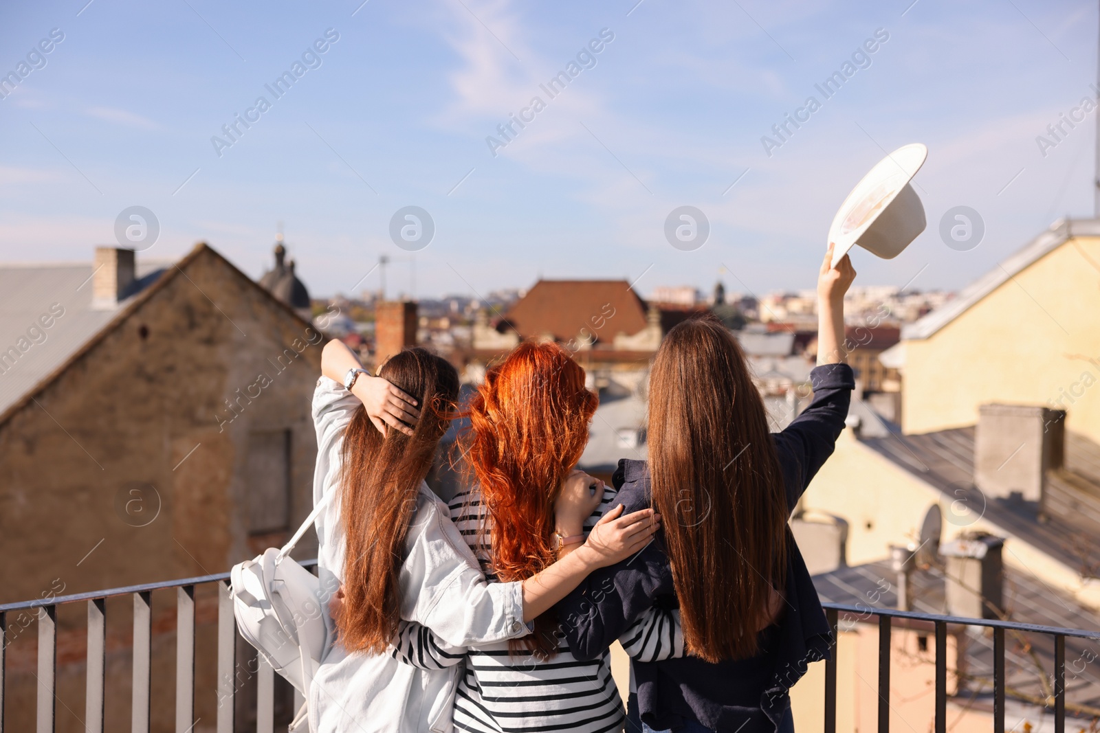 Photo of Friends enjoying of cityscape on balcony, back view
