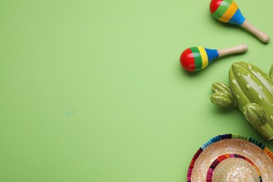 Photo of Colorful maracas, toy cactus and sombrero hat on light green background, flat lay with space for text. Musical instrument