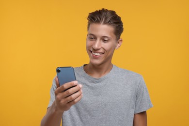Photo of Happy man using smartphone on orange background