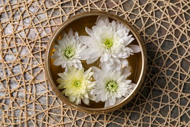 Photo of Tibetan singing bowl with water and beautiful chrysanthemum flowers on table, top view