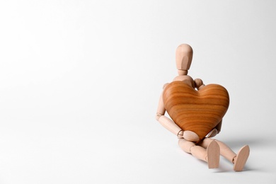 Human mannequin with wooden heart on white background. Space for text