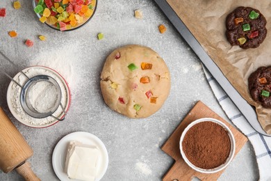 Photo of Unbaked cookies with candied fruits on grey table, flat lay